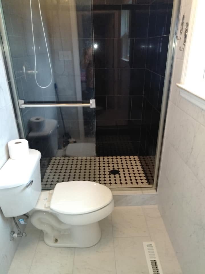 Glass shower enclosure with dark tile and mosaic shower floor