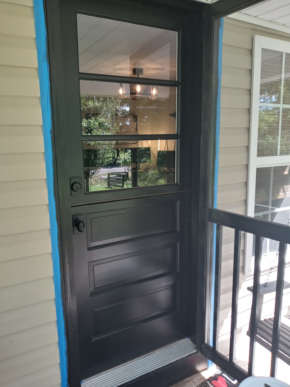Black painted Dutch door with glass panes on a covered porch