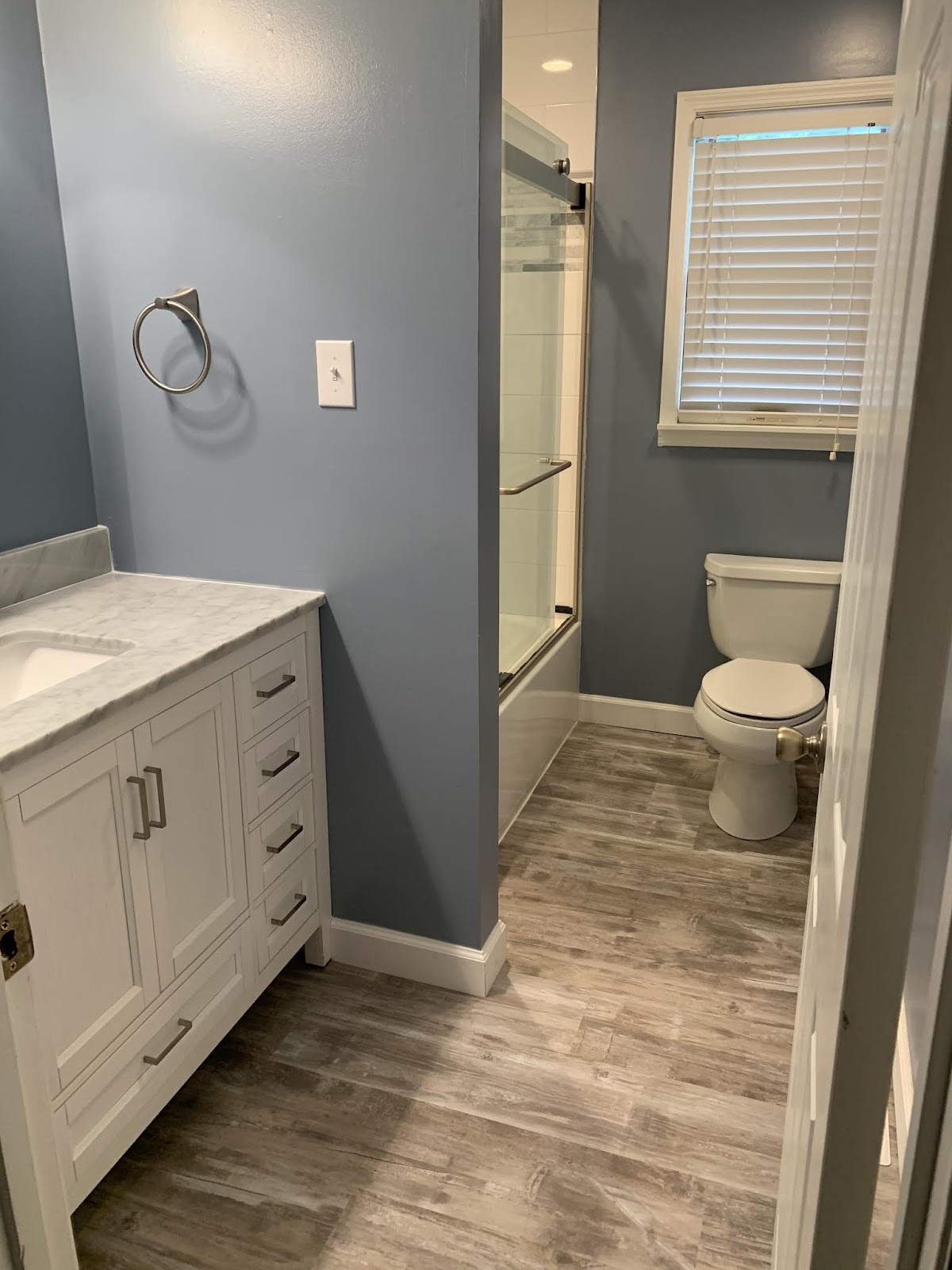 Bathroom remodel with blue walls, white vanity and wood-look luxury vinyl plank flooring