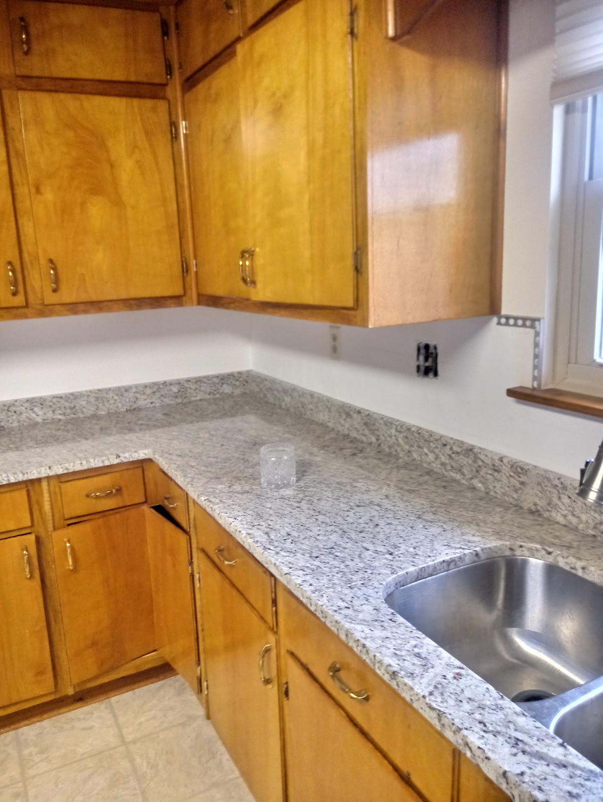 Granite kitchen countertop beside wood cabinets and a stainless steel sink
