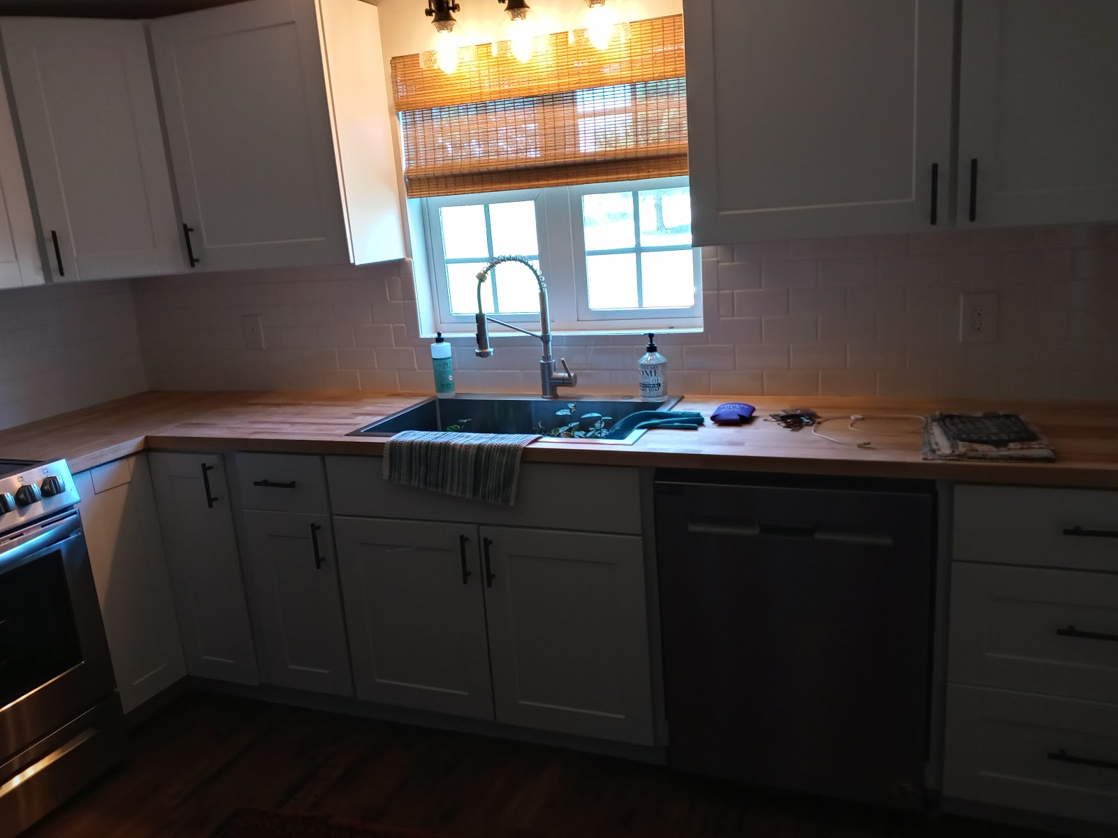 White shaker kitchen cabinets with butcher block counters and subway tile backsplash