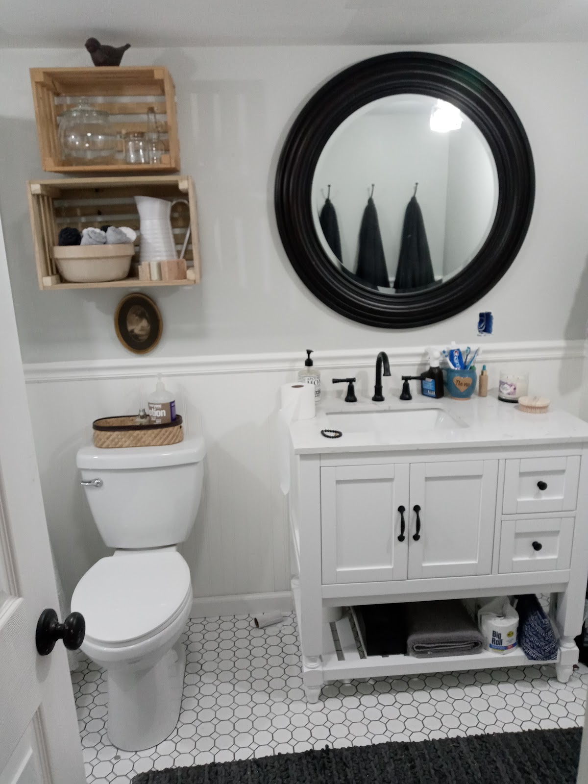 White bathroom vanity with black fixtures and hexagonal tile flooring